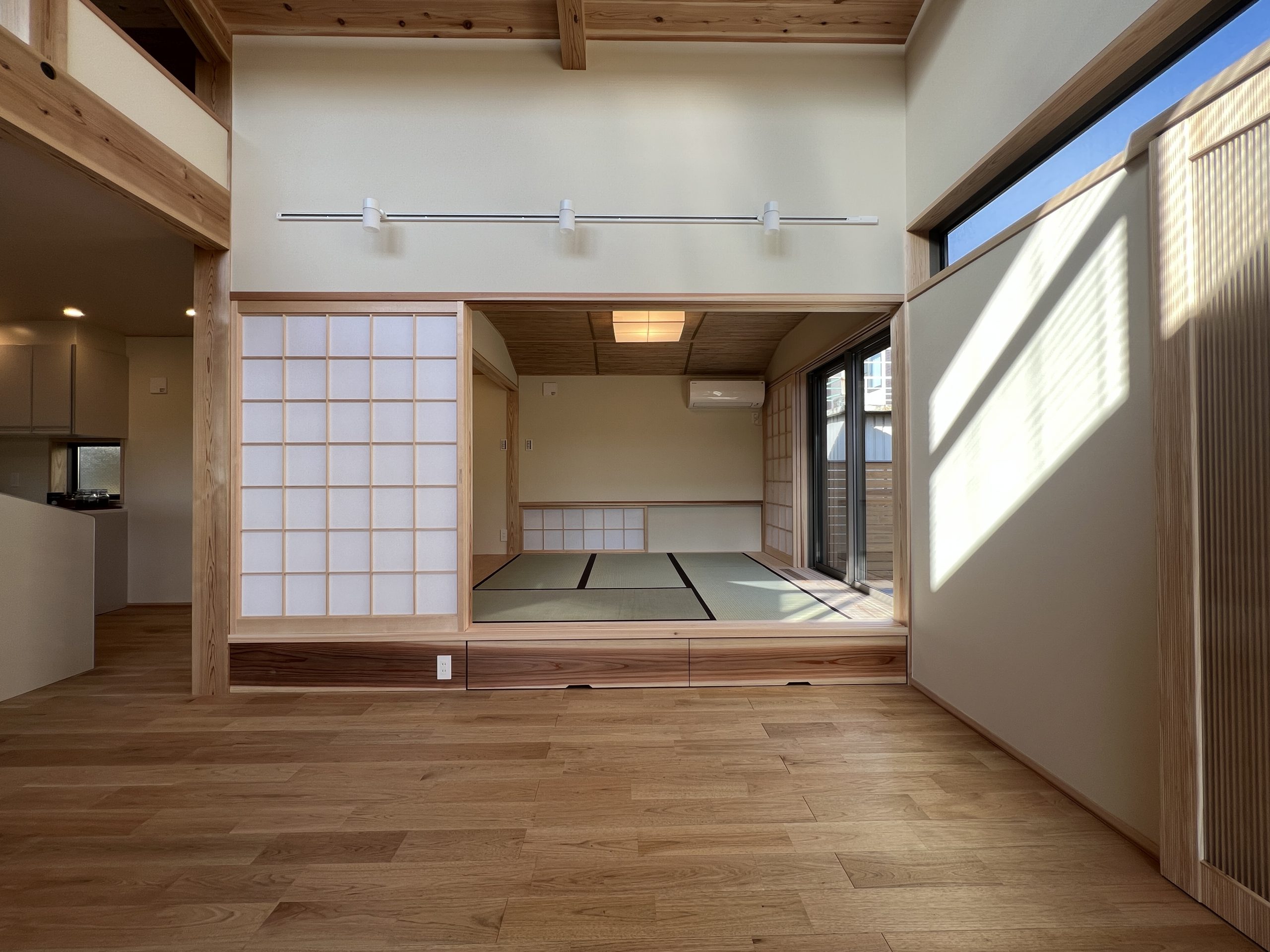 吹抜けに設けた窓から光が降り注ぐリビングは和室と一体に。和室を小上がりにすることで収納も生まれます。