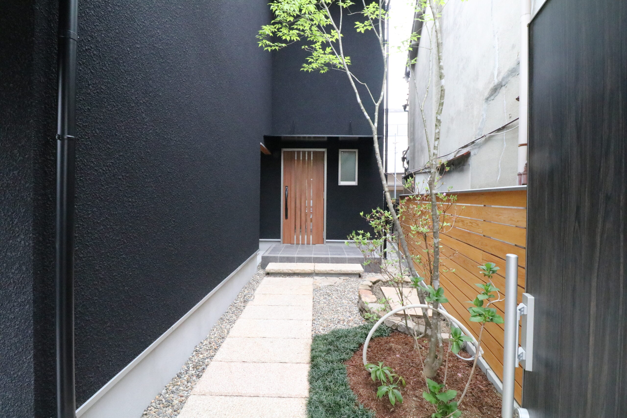 路地のようなアプローチを抜けて玄関へ。ガレージから玄関へとつながる出入口も設けました。
